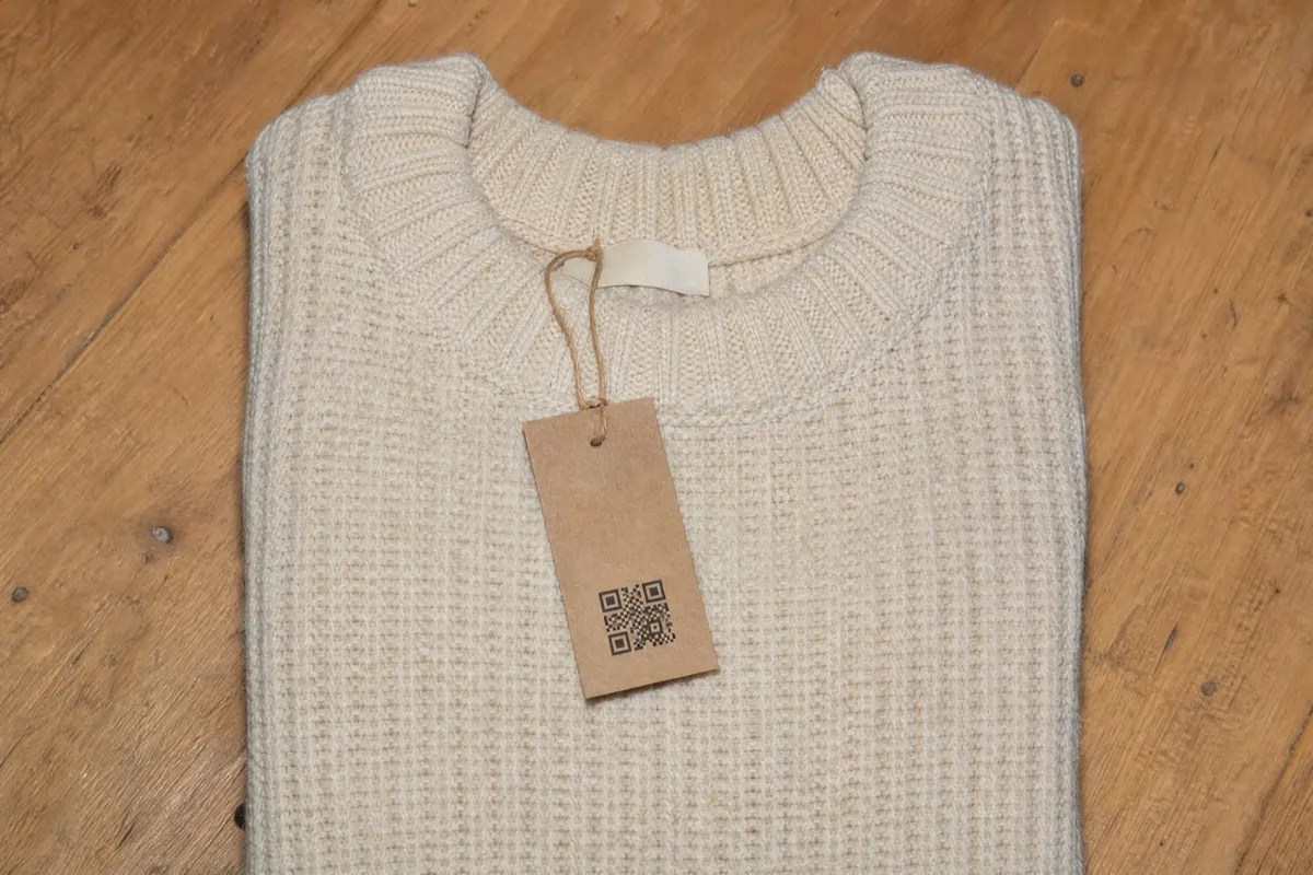 KI-generiertes Bild: Strickpullover mit Hangtag aus Kraftpapier und QR-Code